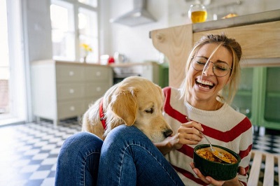 mulher a tomar pequeno almoço com cão