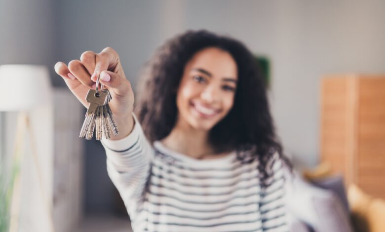 Jovem mulher sorri ao mostrar as chaves de casa, simulando a contratação de um crédito habitação responsável